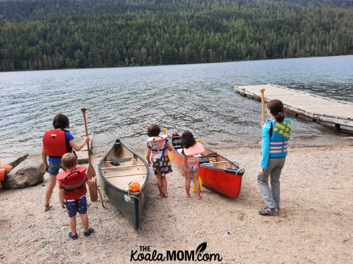 Five kids in life jackets beside two canoes, ready to paddle on Clearwater Lake.