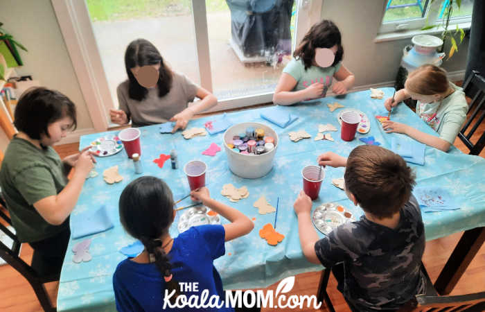 Kids painting wooden butterflies with acrylic paints.
